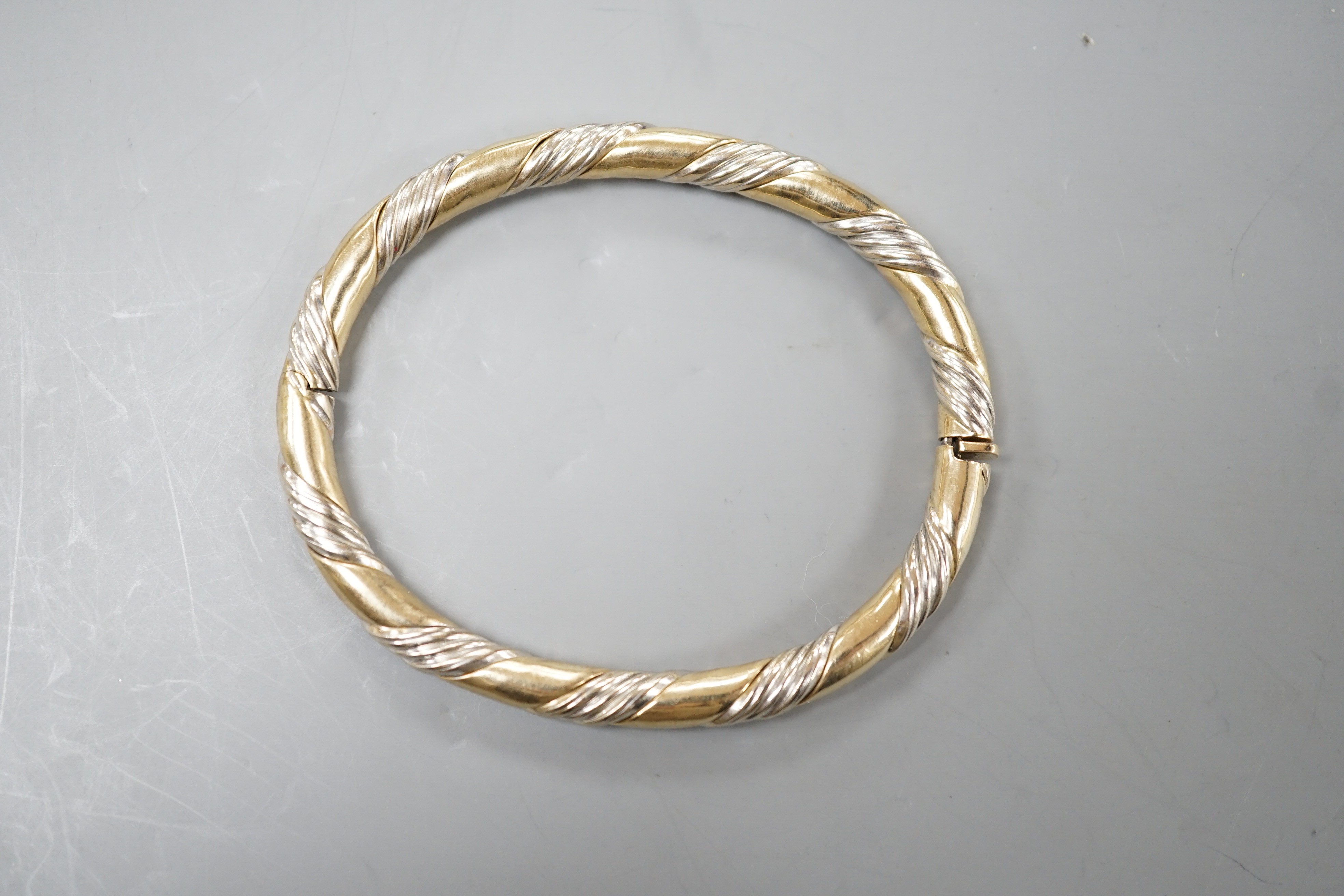 A modern two colour 9ct gold hinged bangle, interior diameter 58mm, 18.7 grams.